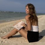jeune femme à la plage qui tient un journal de voyage pour raconter ses souvenirs